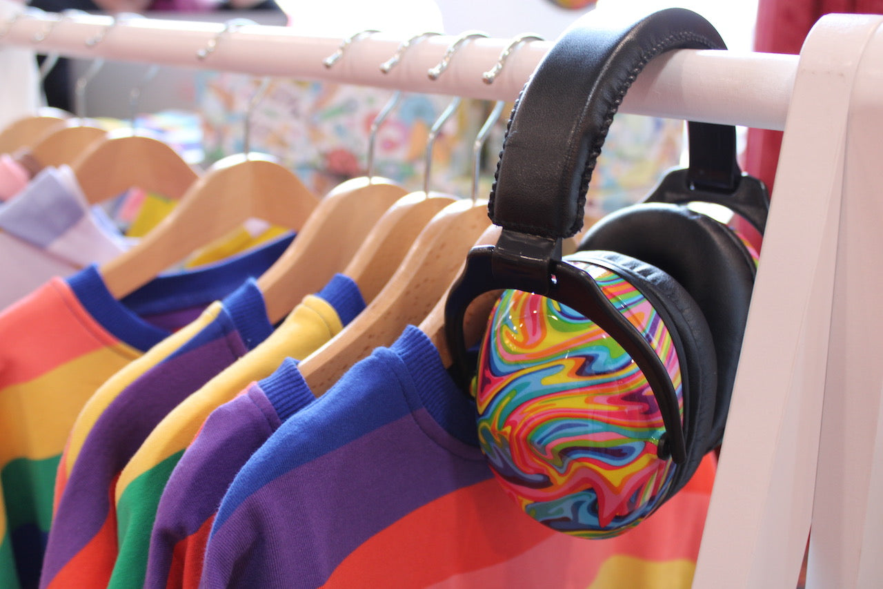 A clothes rail with rainbow ear defenders and jumpers 